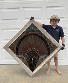 a young boy holding up a large turkey in front of a garage door with his hands on the frame