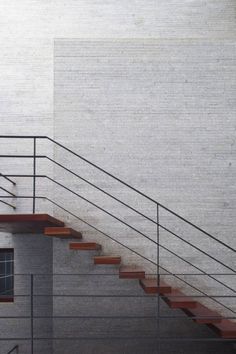 a man riding a skateboard down the side of a metal hand rail next to a white wall