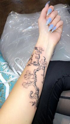 a woman's arm with a flower tattoo on it, sitting next to a plastic bag