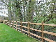 a wooden fence is lined with green grass