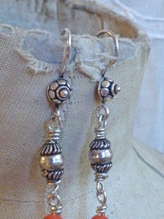 These lovely earrings are made from floral charms in sterling silver, set with sterling beads and coral beads, hanging from sterling Balinese earrings hooks. I love how the bottom charms, with their art nouveau vibe, and reminiscent of feathers. These earrings are long and dramatic but very light weight, and comfortable to wear. All pieces are unique. They are made completely from found and recycled parts, much like found-object art. I have loved jewelry my whole life. I want to create pieces th Bohemian Dangle Jewelry With Lobster Clasp, Coral Dangle Earrings, Bohemian Coral Dangle Earrings, Artisan Red Coral Hand-strung Jewelry, Orange Amulet-style Jewelry With Large Beads, Found Object Art, Coral Beads, Lovely Earrings, Found Object