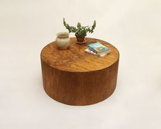 a wooden table topped with a potted plant next to a book on top of it