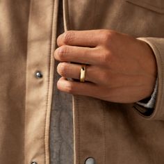 a man's hand with a ring on his left wrist, wearing a tan jacket