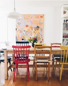 a dining room table with four chairs and a painting on the wall