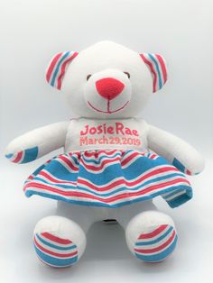 a white teddy bear with red, blue and pink stripes