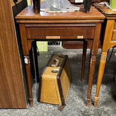 an old suitcase is sitting on the floor next to a table with other antique items