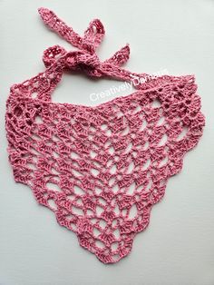 a pink crocheted bib with a bow on it