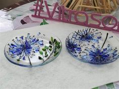 two plates sitting on top of a table covered in blue and white flowers next to a pink sign