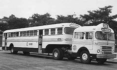 two buses are parked next to each other on the side of the road in black and white