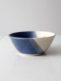 a blue and white striped bowl sitting on top of a table next to a wall