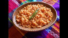 a brown bowl filled with rice on top of a colorful table cloth