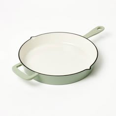 a white and green frying pan on a white surface