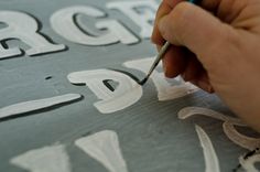 a person is painting letters on a canvas