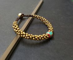 "Single Nepal Handmade Woven Brass Bracelet M a t e r i a l : ♡ brass bead ♡ bell ♡ nepal bead ♡ wax cord S i z e : 7.5\" S h i p p i n g : ♡ All items shipped worldwide by Thailand post. ♡ Shipped within 2- 3 days after payment received. ♡ Can be upgrade to express mail by a request before payment. You will take : ♡ 15 - 25 days after shipped from Thailand . ♡ 5- 7 days after shipped from Thailand by express mail." Gold Hand-strung Braided Bracelet For Festivals, Adjustable Beaded Bracelets For Rituals, Hand-strung Brass Bracelets With Round Beads, Bohemian Gold Braided Bracelet With Round Beads, Bohemian Gold Braided Bracelet With Beads, Handmade Spiritual Brass Beaded Bracelets, Brass Beaded Bracelets With Round Beads, Brass Beaded Bracelets For Festivals, Adjustable Gold Bead Brass Bracelets