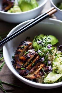 a bowl filled with meat and vegetables next to chopsticks on top of a wooden table