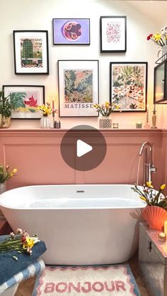 a bathroom with pictures on the wall and a bathtub in front of a sink