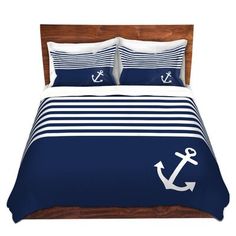 a bed with blue and white striped comforter set that has an anchor on it