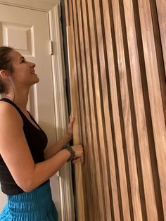 a woman standing next to a wooden door and holding onto the side of a wall