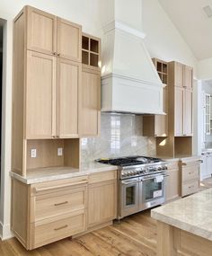 a large kitchen with wooden cabinets and white marble counter tops, along with stainless steel appliances