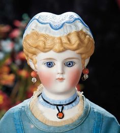 a close up of a doll with blue eyes and blonde hair, wearing a blue dress