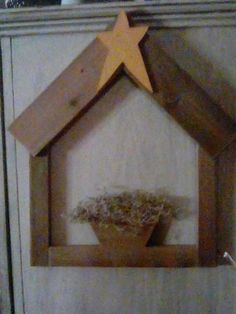 a small wooden house with a star on the top and a plant in it's center