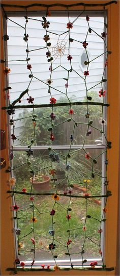 the window is decorated with beads and flowers on it's glass rod, along with a spider web