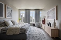 a bedroom with a large bed sitting next to a window covered in gray and white curtains