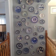 a wall mounted with plates on it next to a banister