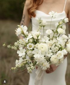 a woman holding a bouquet of white flowers