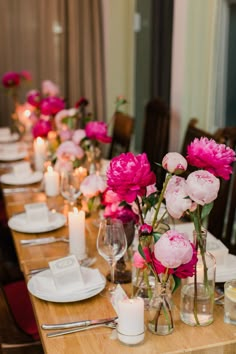 a long table is set with pink flowers and candles for a formal dinner or party