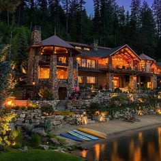 a large house sitting on top of a lush green hillside next to a body of water