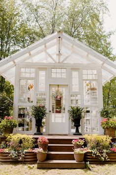 a white house with potted plants on the steps