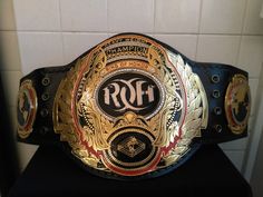 a gold and black belt sitting on top of a counter next to a white tile wall