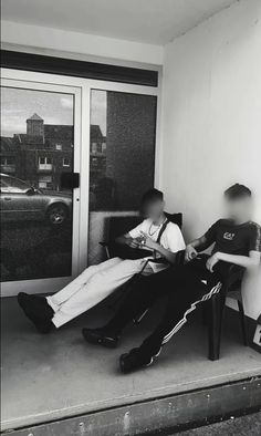 two people sitting on a bench in front of a door and one person reading a book