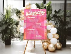 a pink and white sign sitting on top of a wooden easel next to balloons