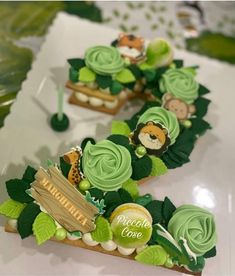 some cupcakes are decorated with green icing and jungle animals on top of them