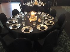 a table set with plates, silverware and candles for an event or function in a large room