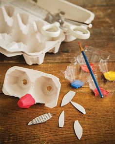 several different types of plastic objects on a wooden table, including an egg carton and scissors