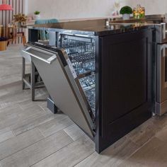 an open dishwasher in the middle of a kitchen with stainless steel appliances and wood flooring