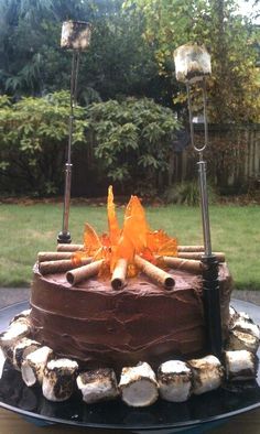 a chocolate cake sitting on top of a black plate covered in frosting and logs