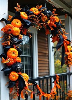 an orange and black wreath with pumpkins on the front porch, decorated for halloween