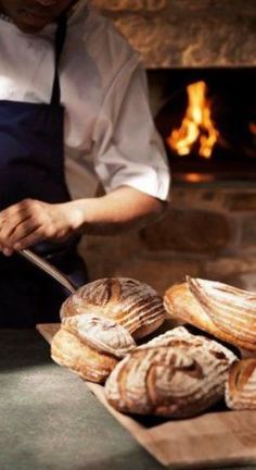 a man in an apron is cutting bread on a table with other breads and pastries