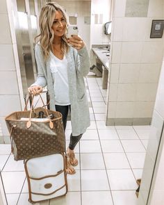 a woman is taking a selfie in the bathroom with her purse and handbag