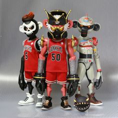 three figurines are standing next to each other in front of a gray background