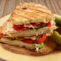 a grilled sandwich on a plate with pickles