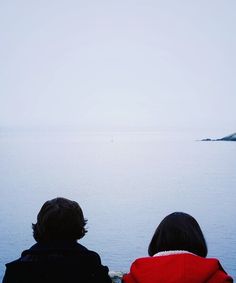 two people looking out over the water at an island