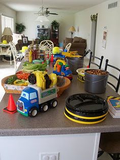 a toy truck is parked on the kitchen counter in front of a table full of children's toys