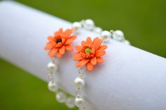 two orange flowers are attached to pearls