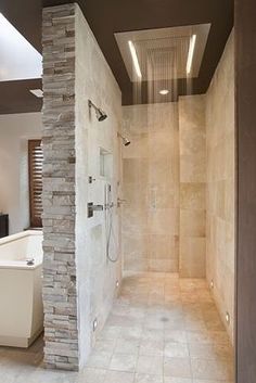 a walk in shower sitting next to a white bath tub under a skylight on top of a tiled floor