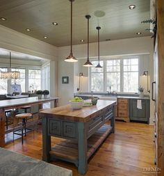 a large kitchen with an island in the middle and two lights hanging from the ceiling